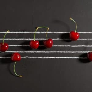 Photo d'une partition de musique écrite avec des cerises rouges.